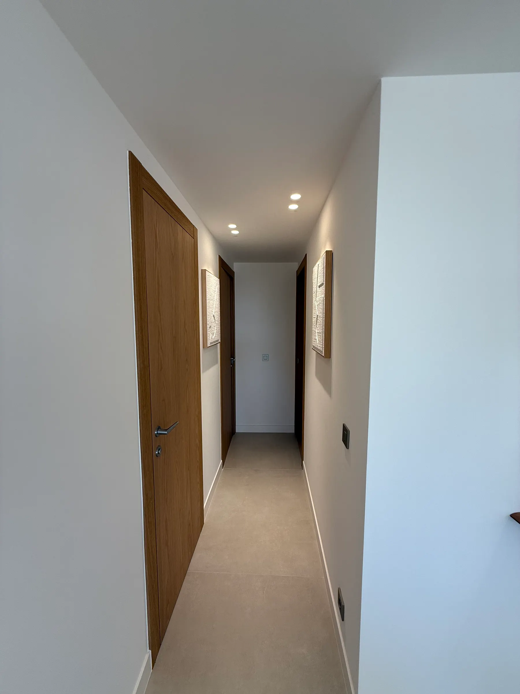Couloir avec portes bois pleine hauteur et sol clair, appartement rénové à Cannes