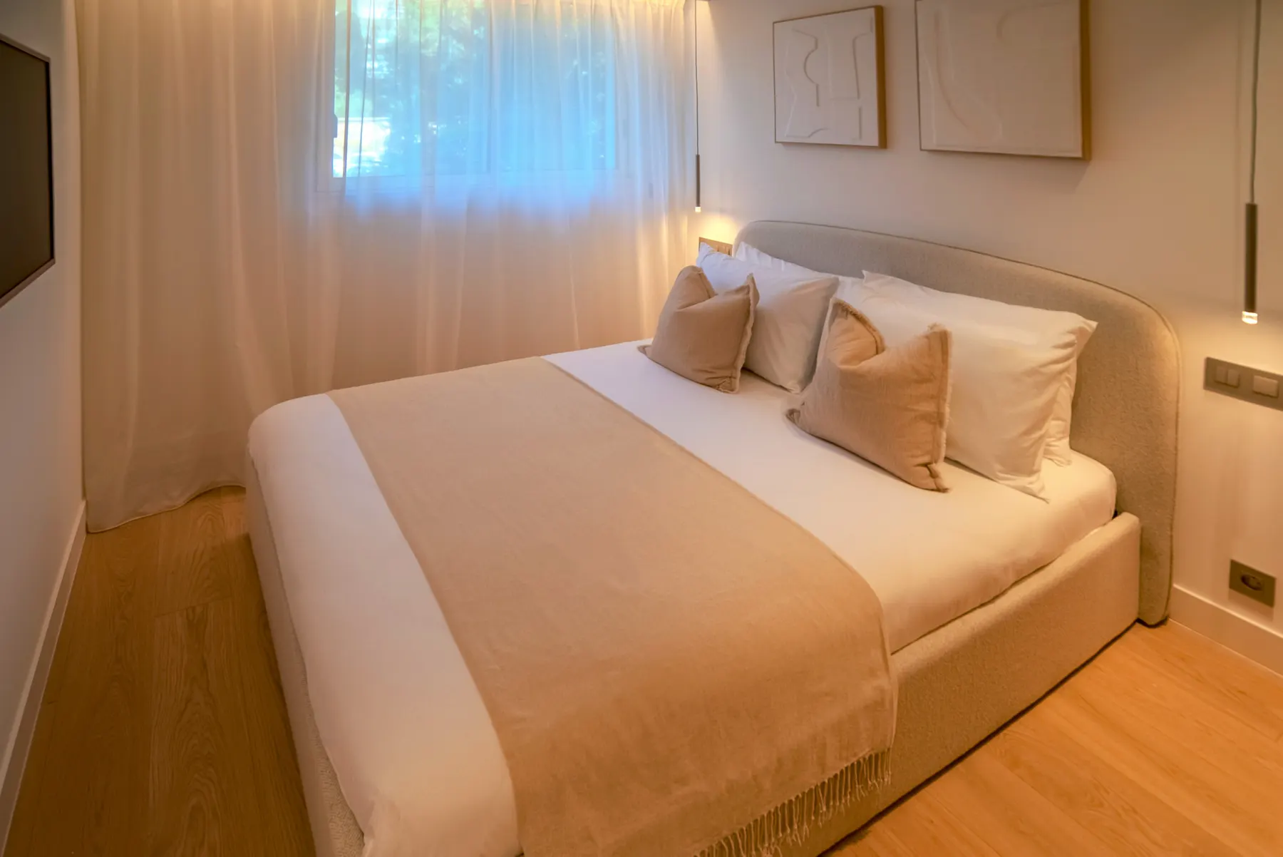 Chambre avec tête de lit arrondie, parquet chêne et suspensions