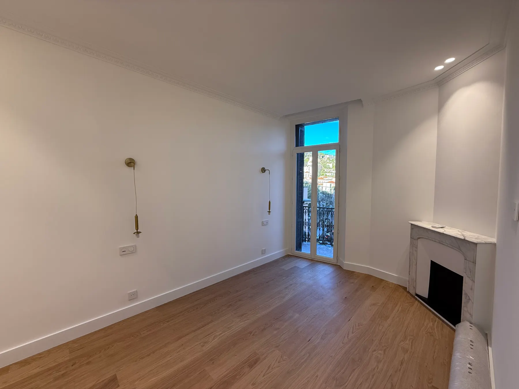 Pièce rénovée avec cheminée en marbre et porte-fenêtre