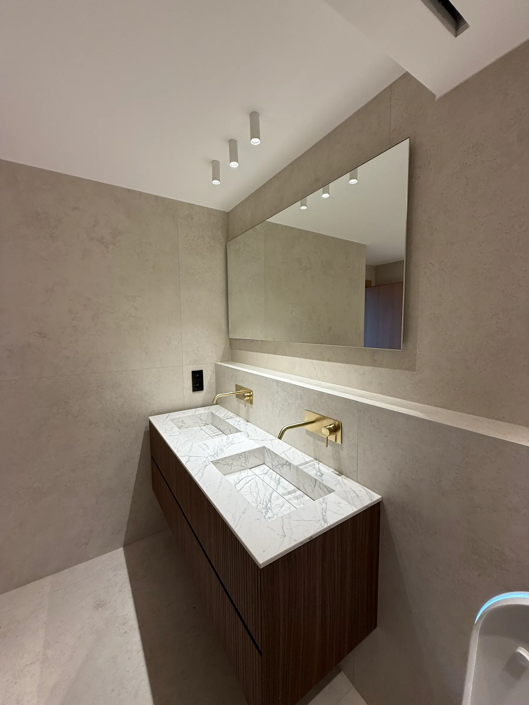 Vasque en pierre et robinetterie laiton dans une salle de bains rénovée
