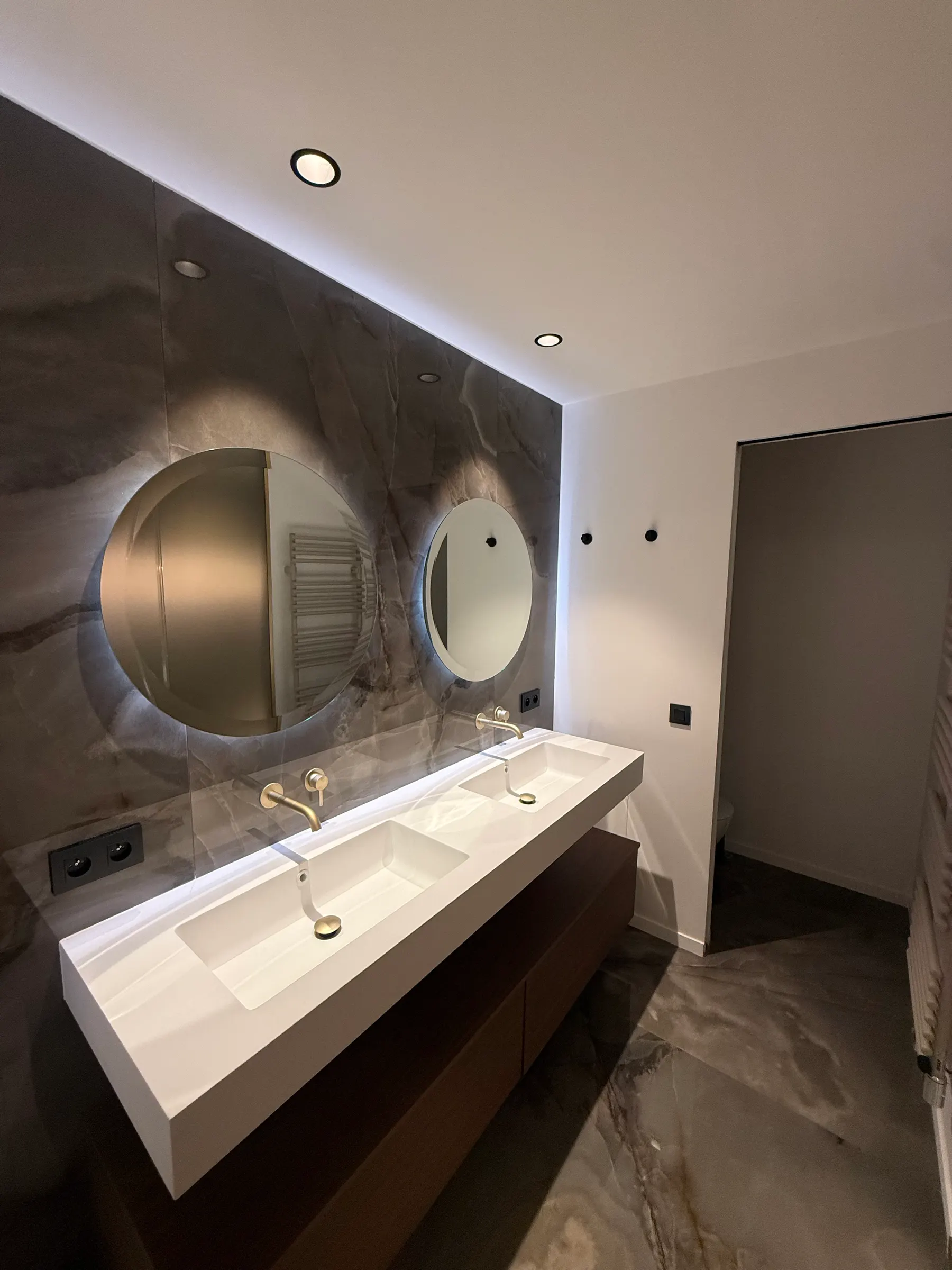 Salle de bains avec double vasque, miroirs ronds et mur en pierre