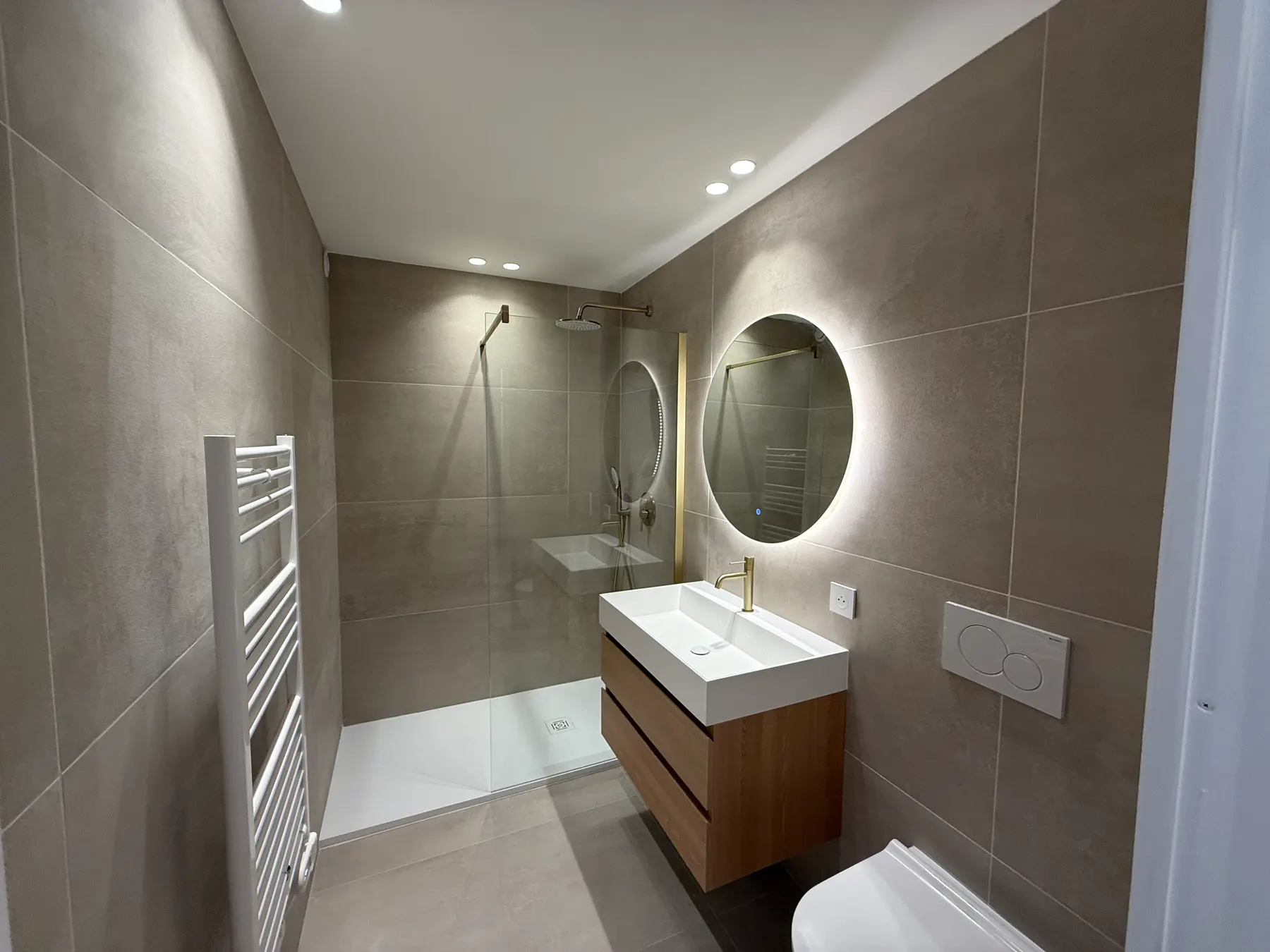 Salle d'eau en carrelage gris grand format avec miroir rond rétroéclairé, Nice