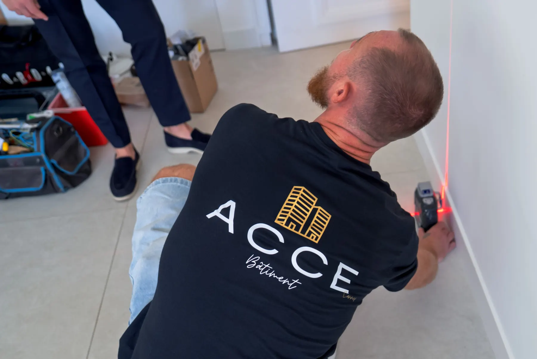 Compagnon d'Acce Bâtiment réglant un niveau laser sur le chantier