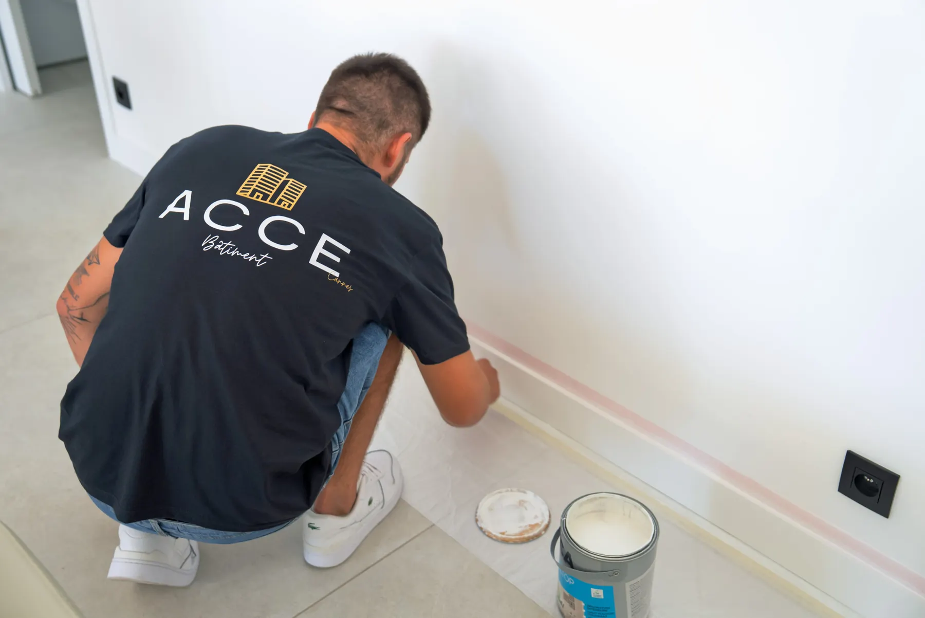 Peintre d'Acce Bâtiment en finition de plinthes dans un appartement