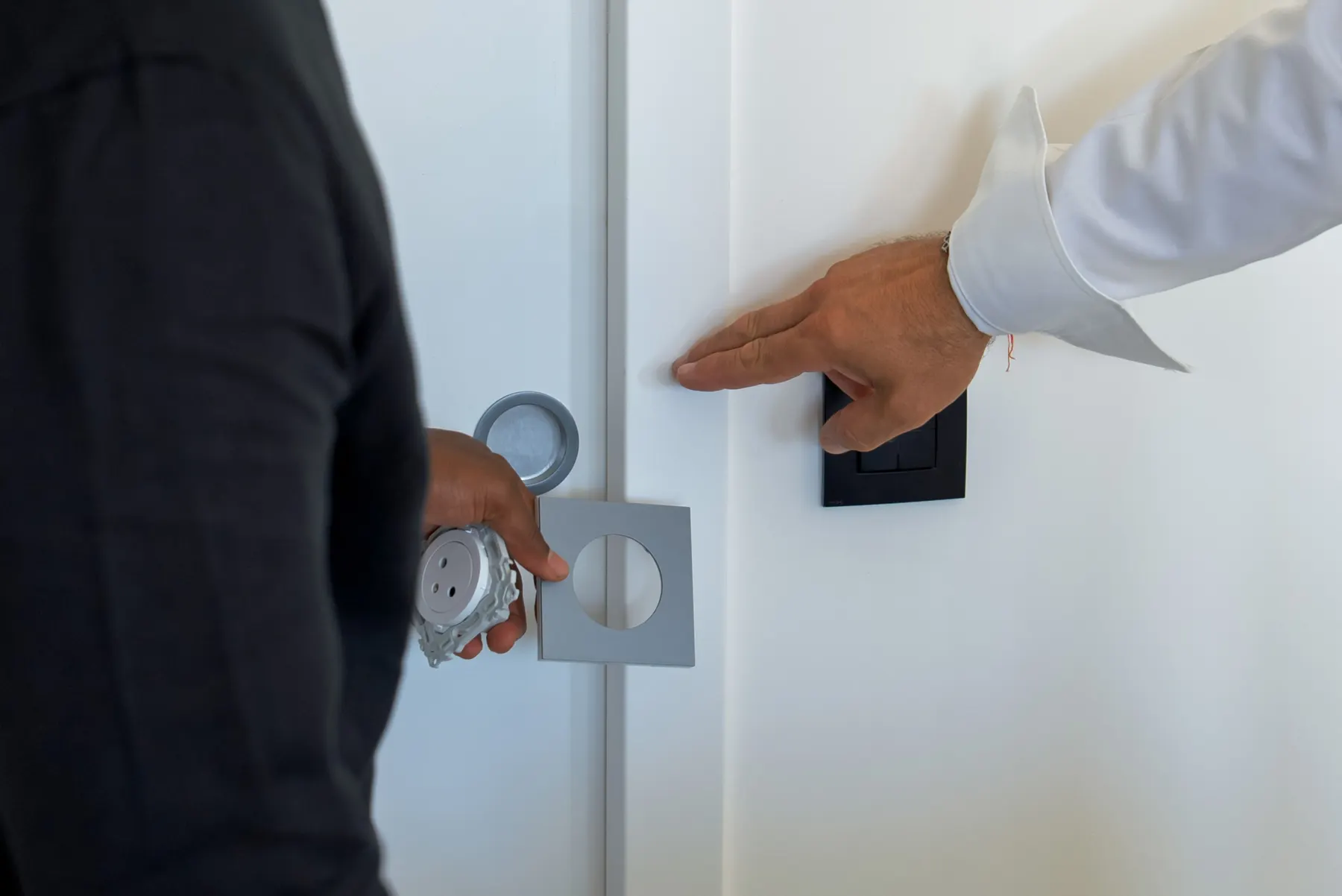 Présentation d'un interrupteur noir et d'une plaque de prise sur le mur