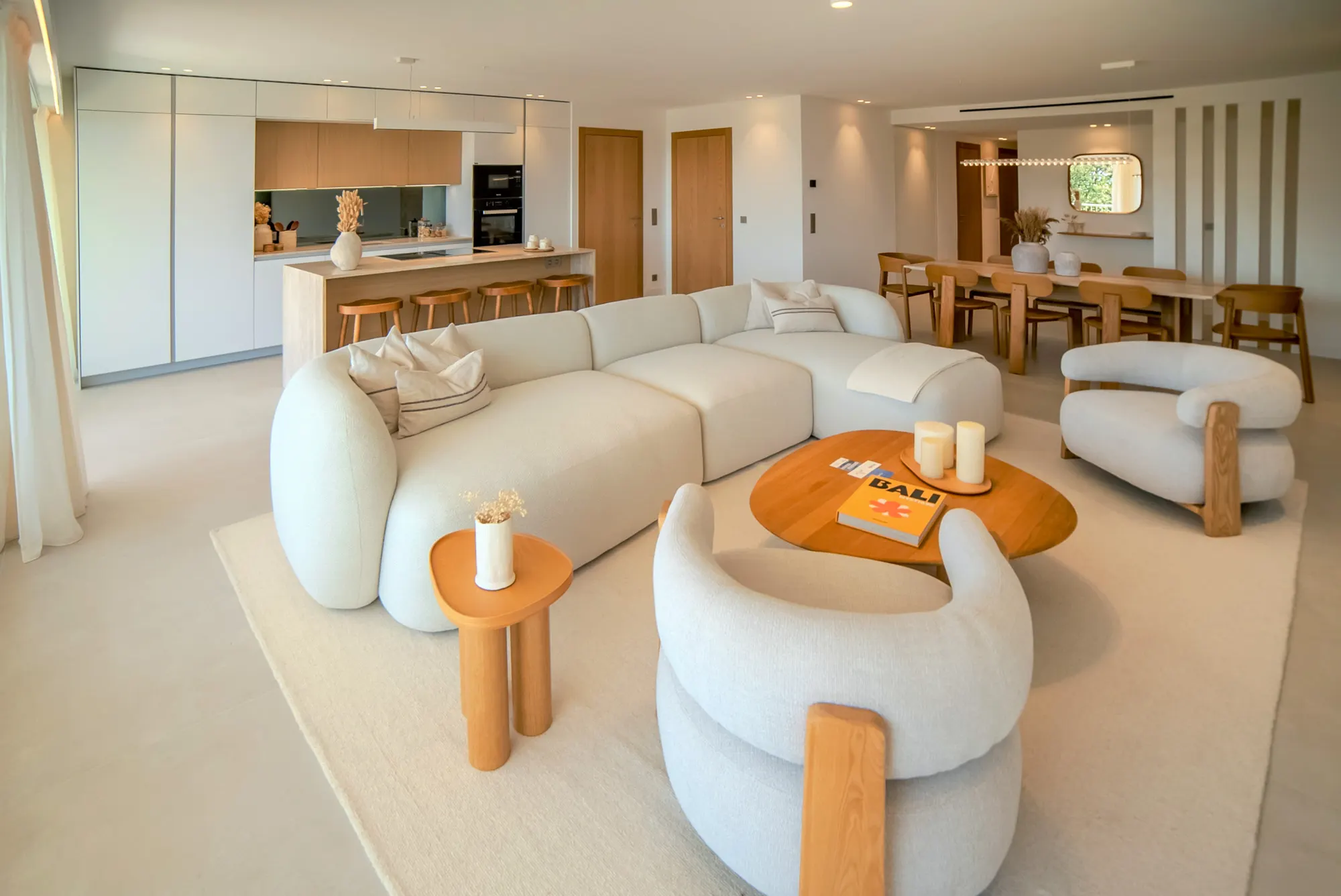 Salon d'un appartement rénové à Cannes, canapé arrondi et cuisine ouverte